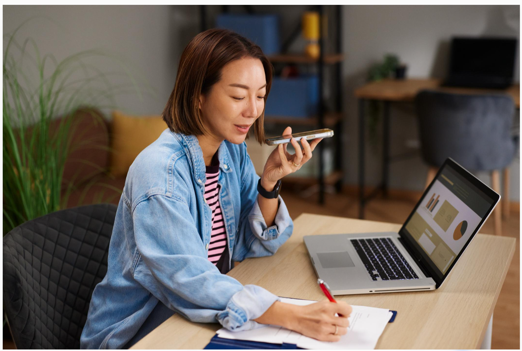 A woman dictating an idea into her phone at her desk